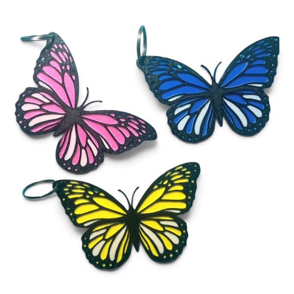 3D printed butterfly keyring set of 3 - pink, blue and yellow on white background